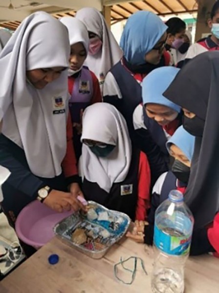 A group of students grouped around a desk use props and materials 